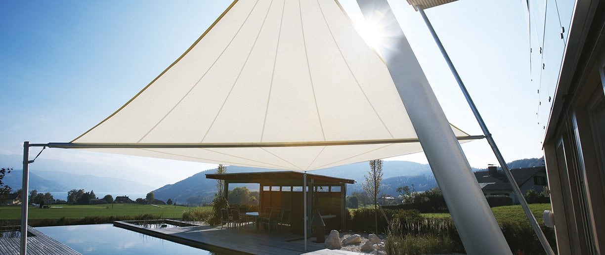 Weißes aufrollbares Sonnensegel über einem Pool mit Bergpanorama